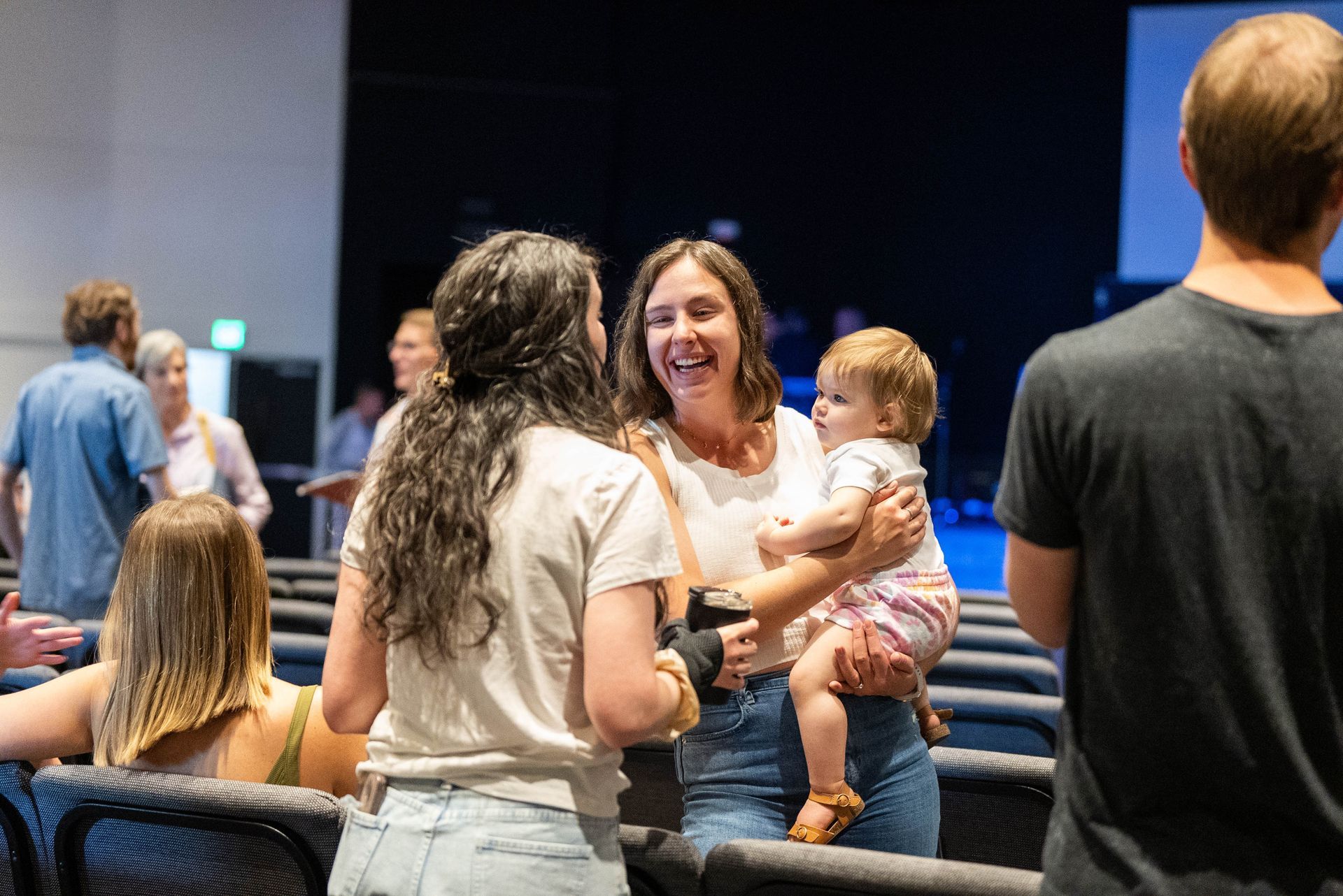 A woman is holding a baby in her arms while talking to another woman.