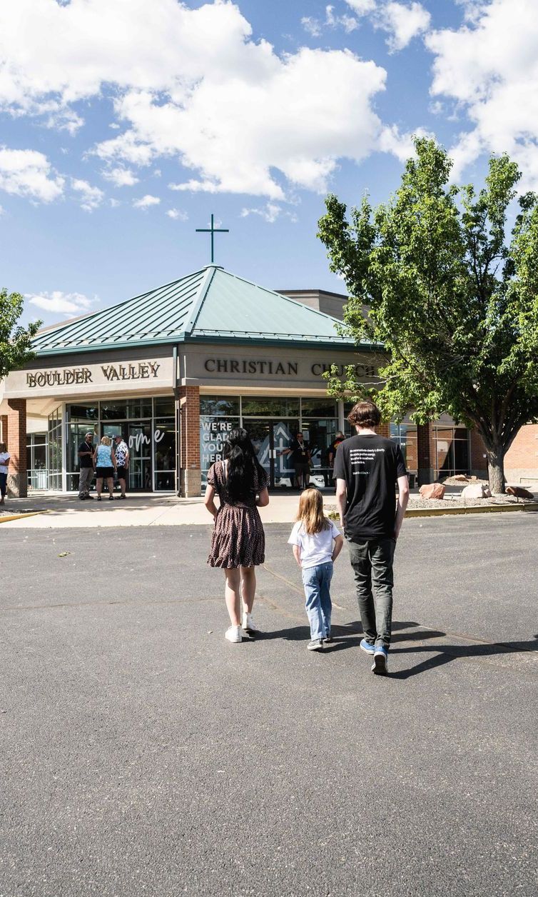 A group of people are walking down a street in front of a church.