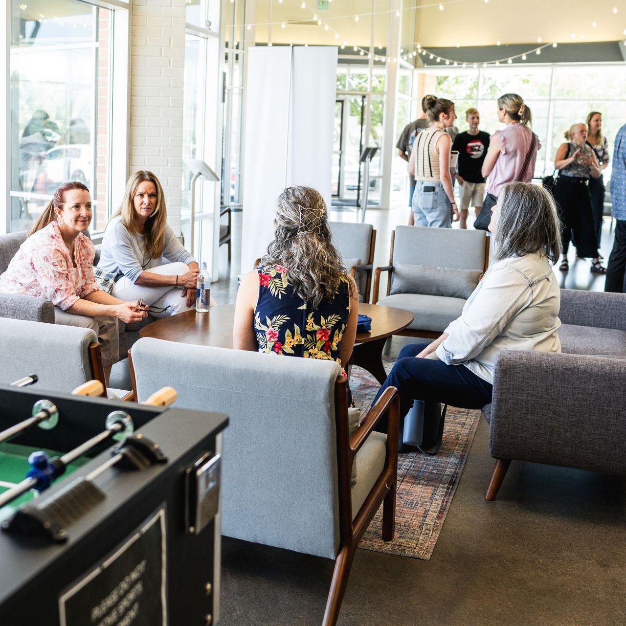 A group of people are sitting in a room with a foosball table