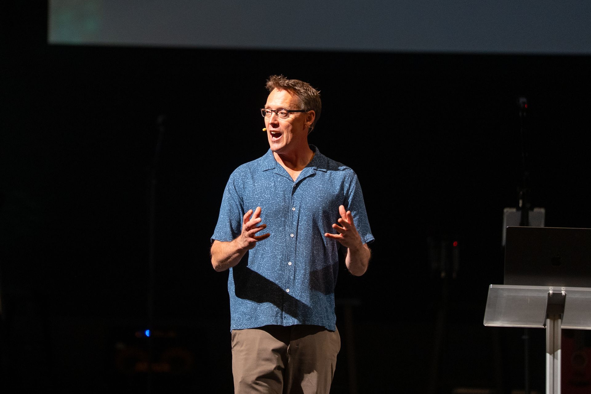 A man is sitting at a table holding a microphone.