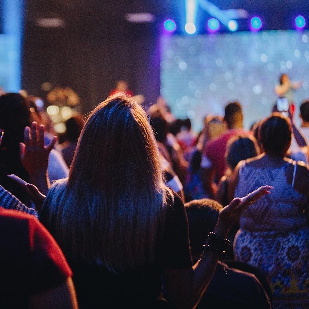 A crowd of people are sitting in front of a stage at a concert.