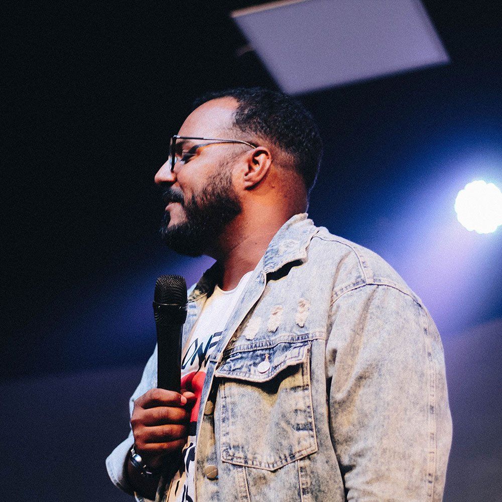 A man in a denim jacket is holding a microphone