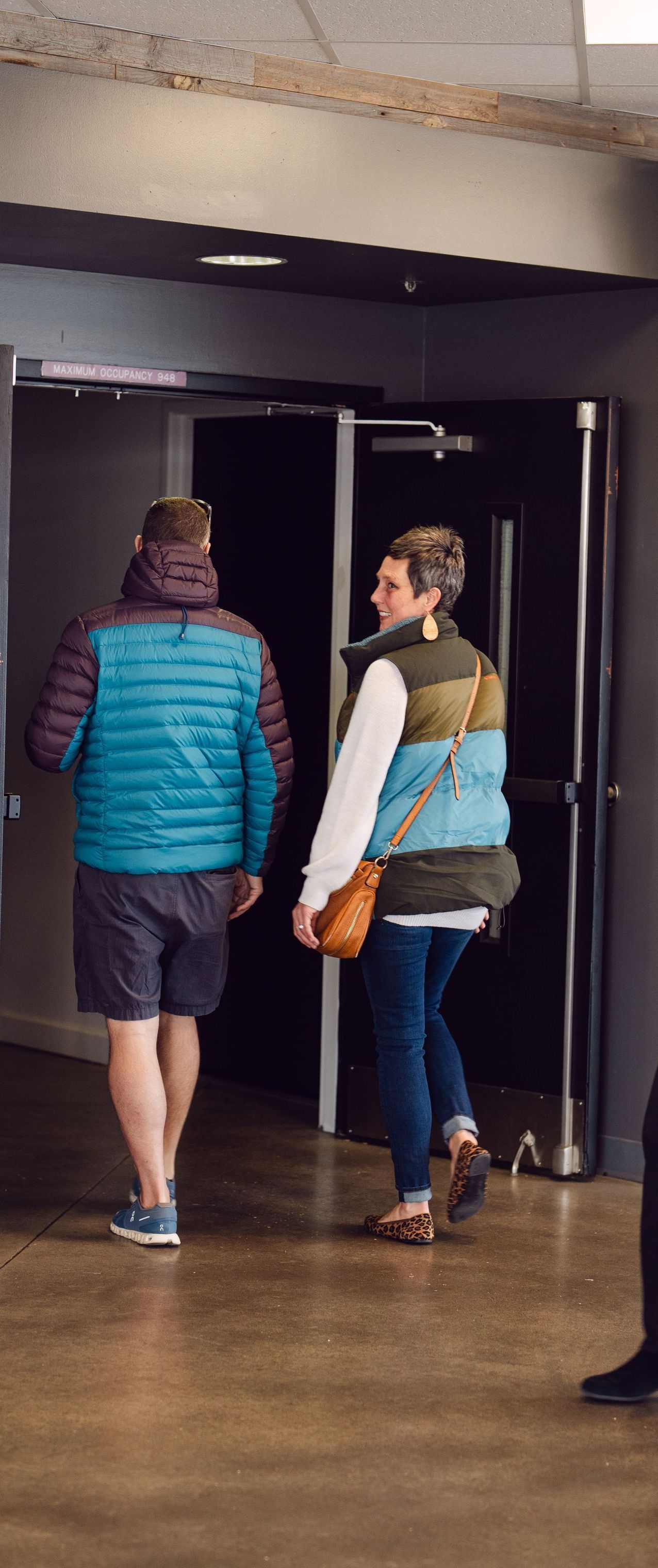 A man and a woman are walking down a hallway.