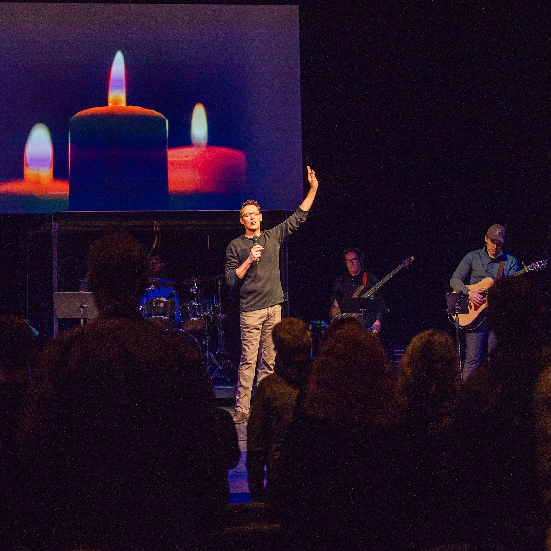 A man stands in front of a large screen with candles on it