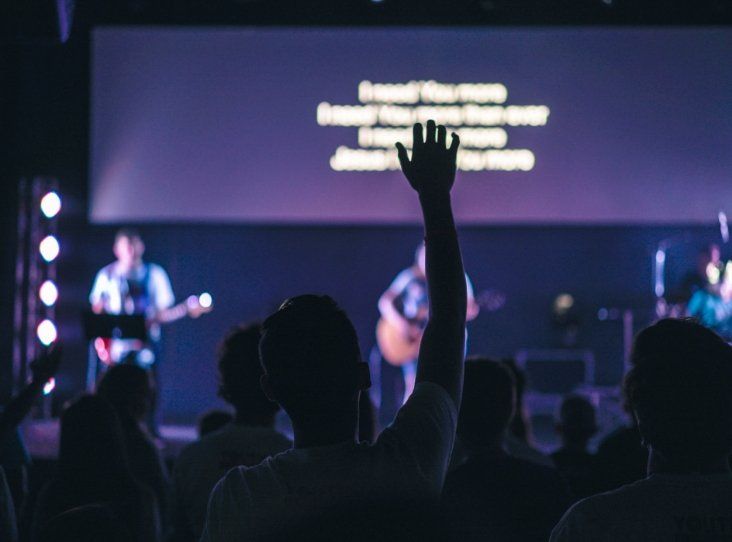 A man is raising his hand in the air at a concert.