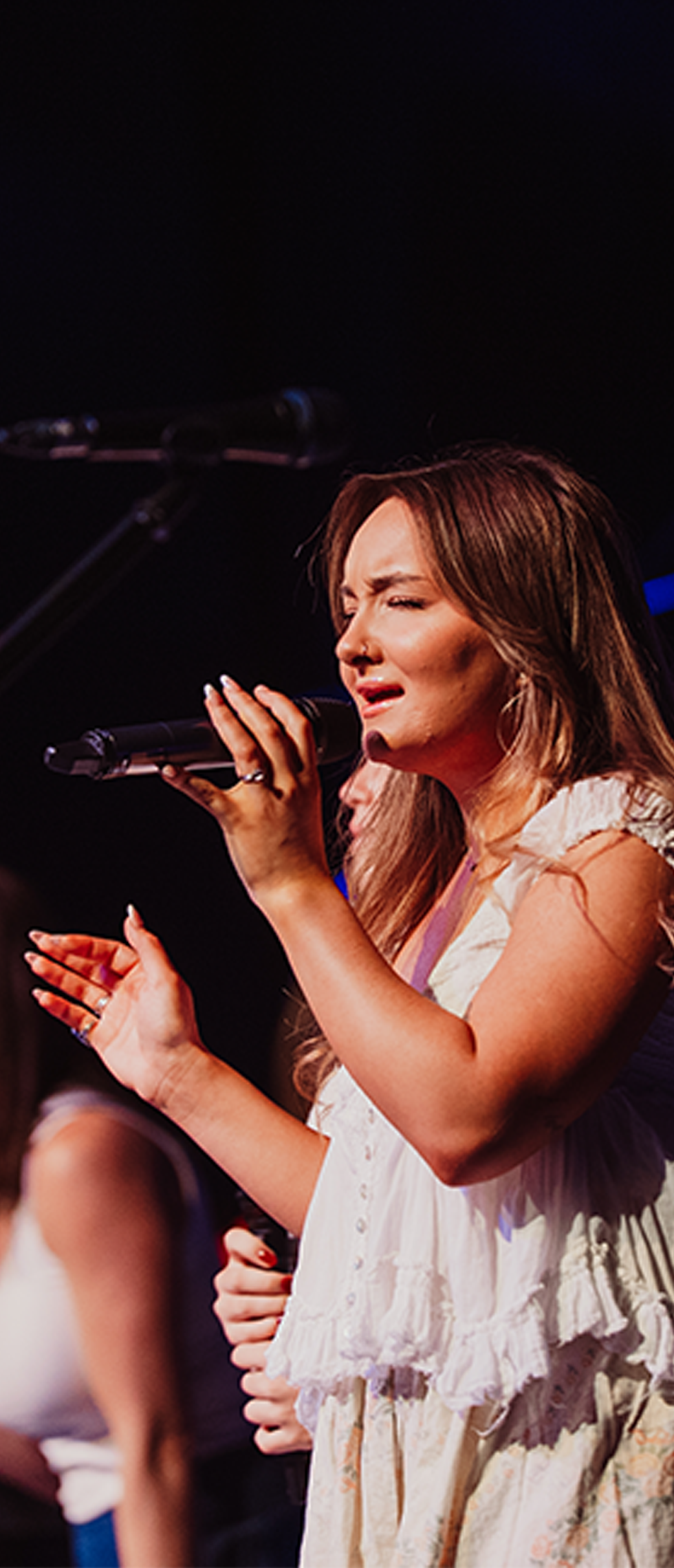 A woman is singing into a microphone on a stage.