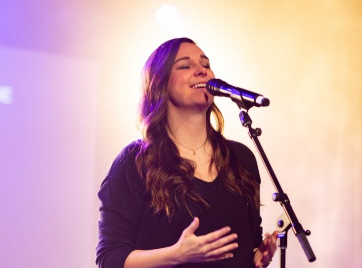 A woman is singing into a microphone on a stage.