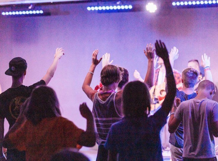 A group of people are dancing on a stage with their hands in the air.