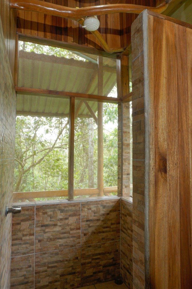 Shower with wood and tile, open to a jungle view.