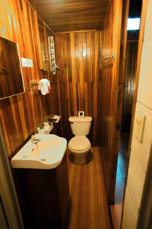 Small bathroom with wood paneling, toilet, sink, and open doorway.