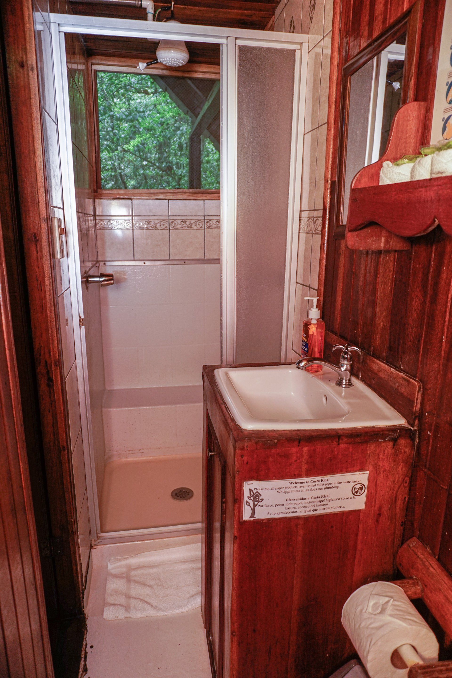 Small rustic bathroom with wooden walls and a shower stall.