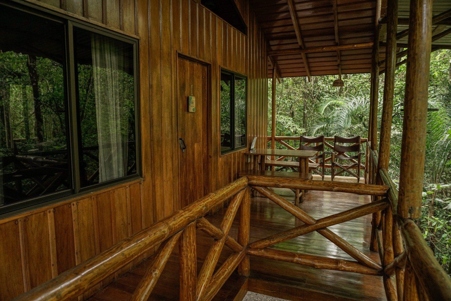 Wooden cabin porch overlooking lush rainforest.