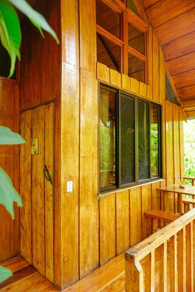 Wooden cabin exterior with a door, window, and railing.