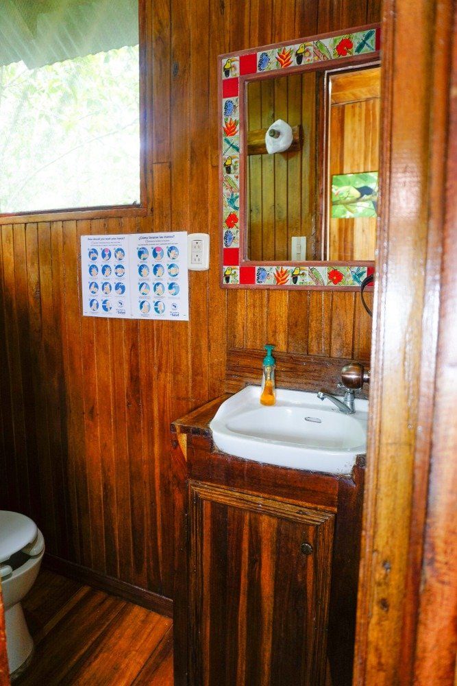 Bathroom with wood paneling, sink, mirror, and hygiene instructions.