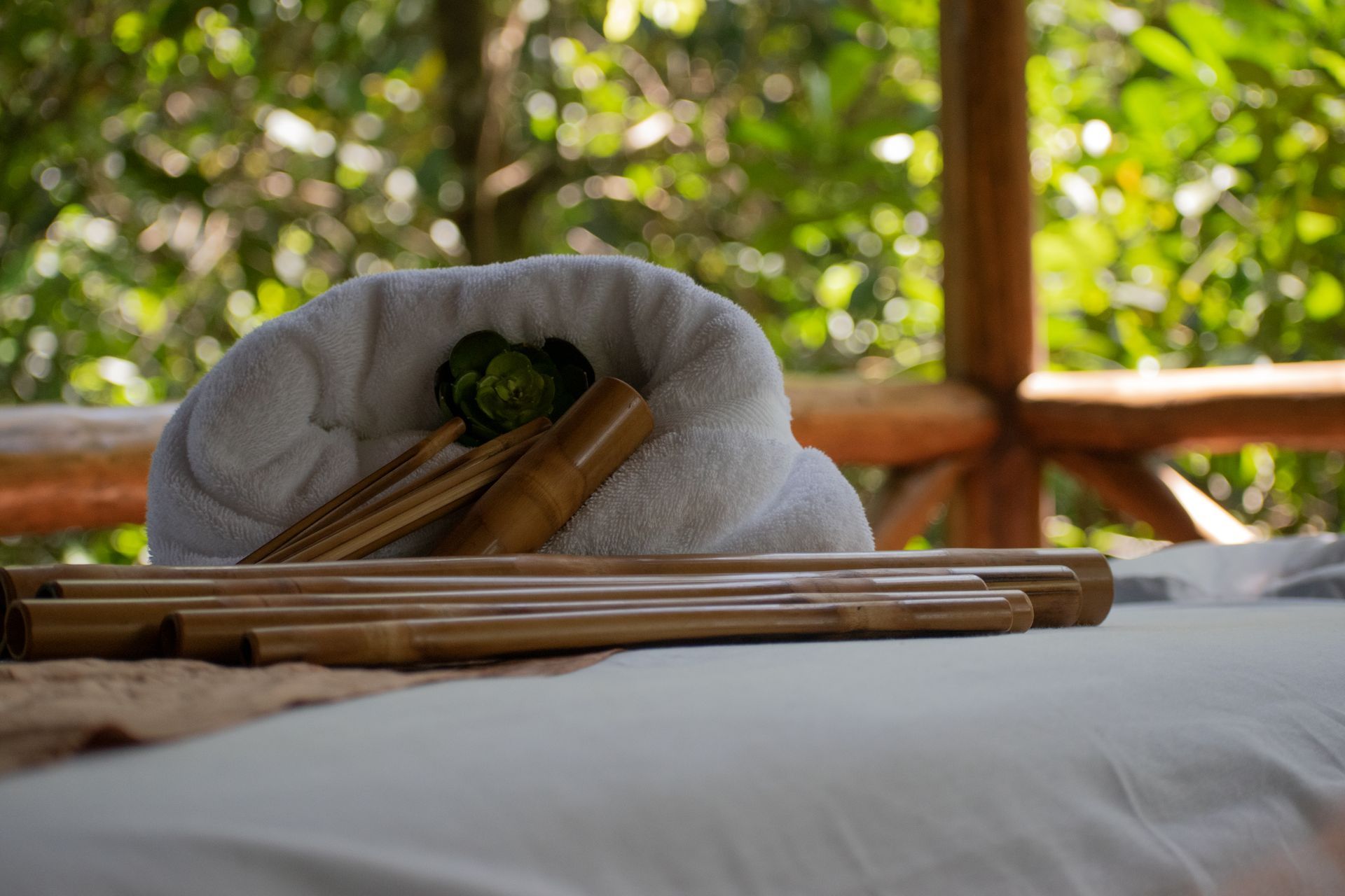 Spa setup with bamboo massage tools and white towel on a massage table outdoors.