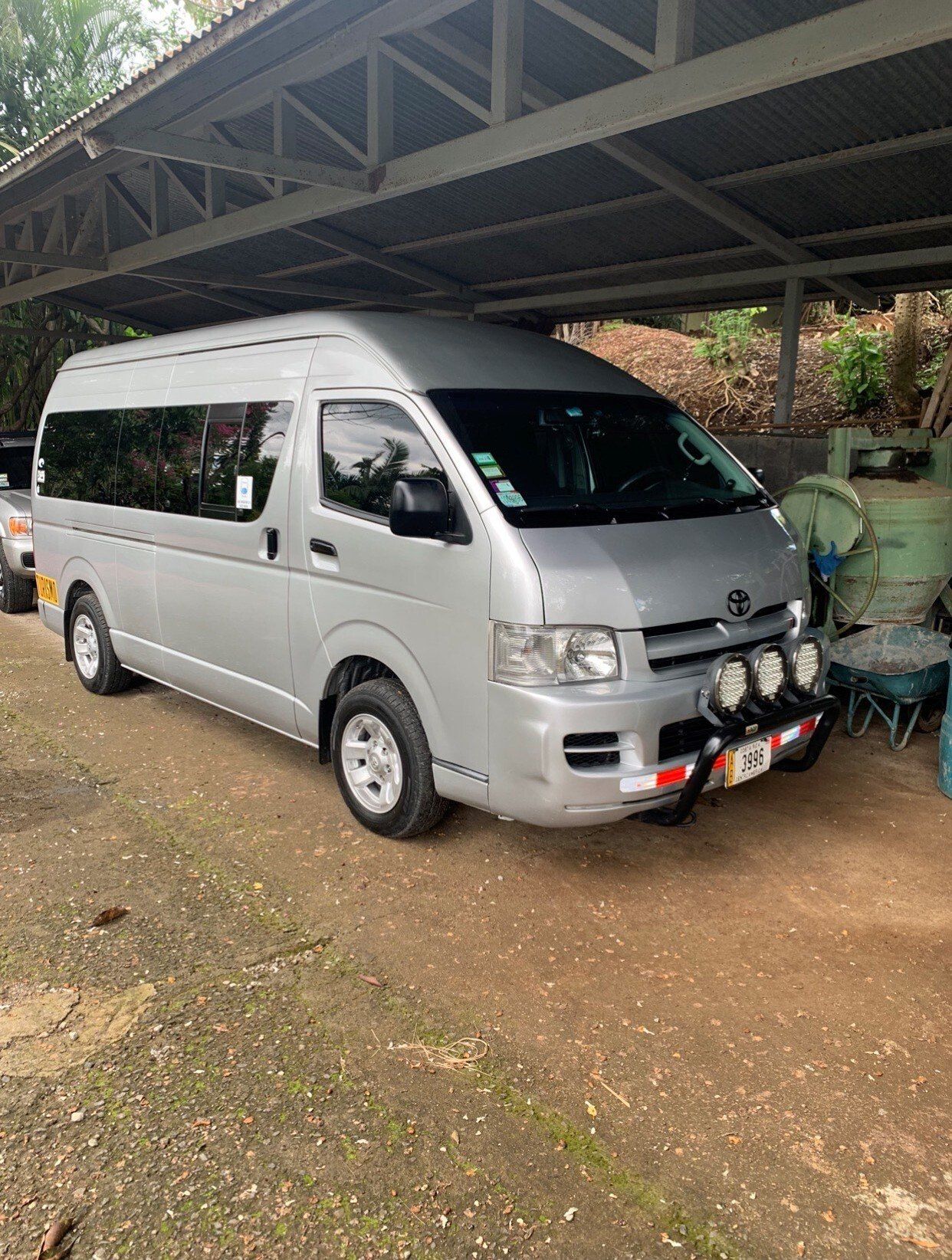 Silver Toyota Hiace van parked under a metal roof.