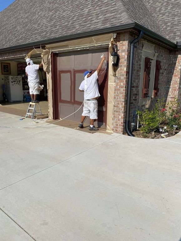 Two painters in white coveralls painting a house garage and exterior trim
