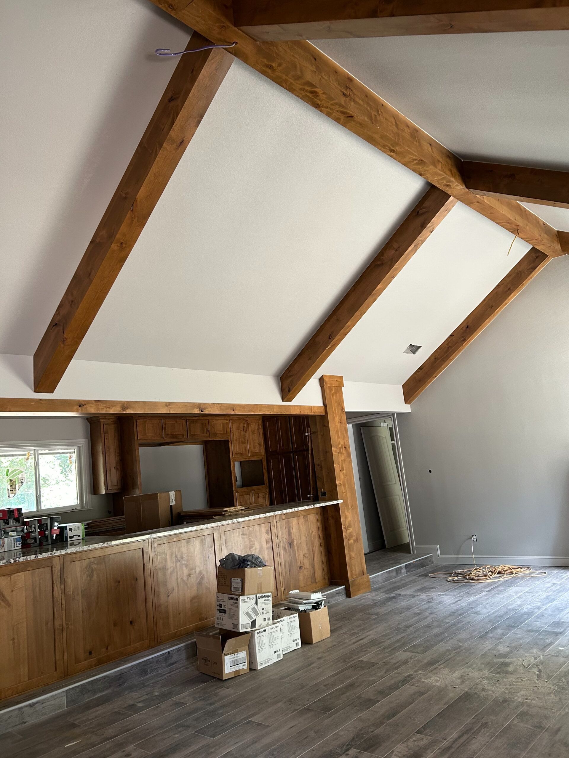 Rustic interior with exposed wood beams, open bar counter, and stacked boxes on a worn floor
