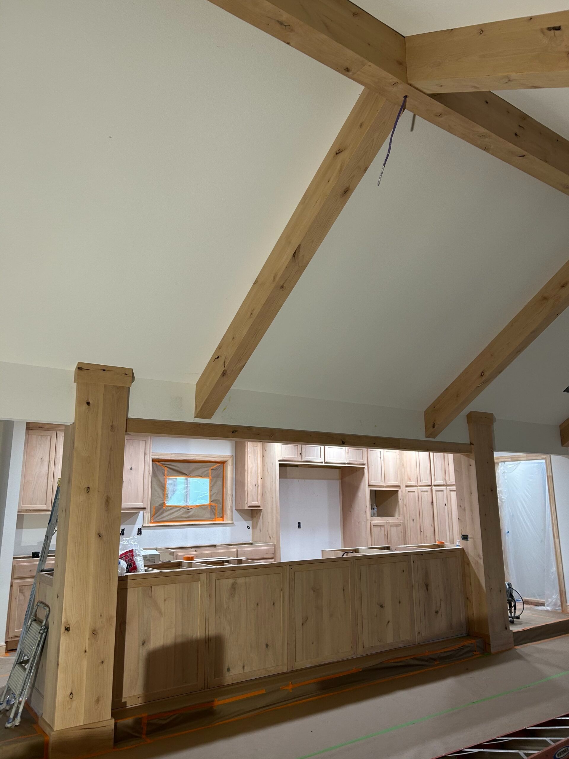 Rustic interior with exposed wooden beams and a long wooden counter under a sloped white ceiling