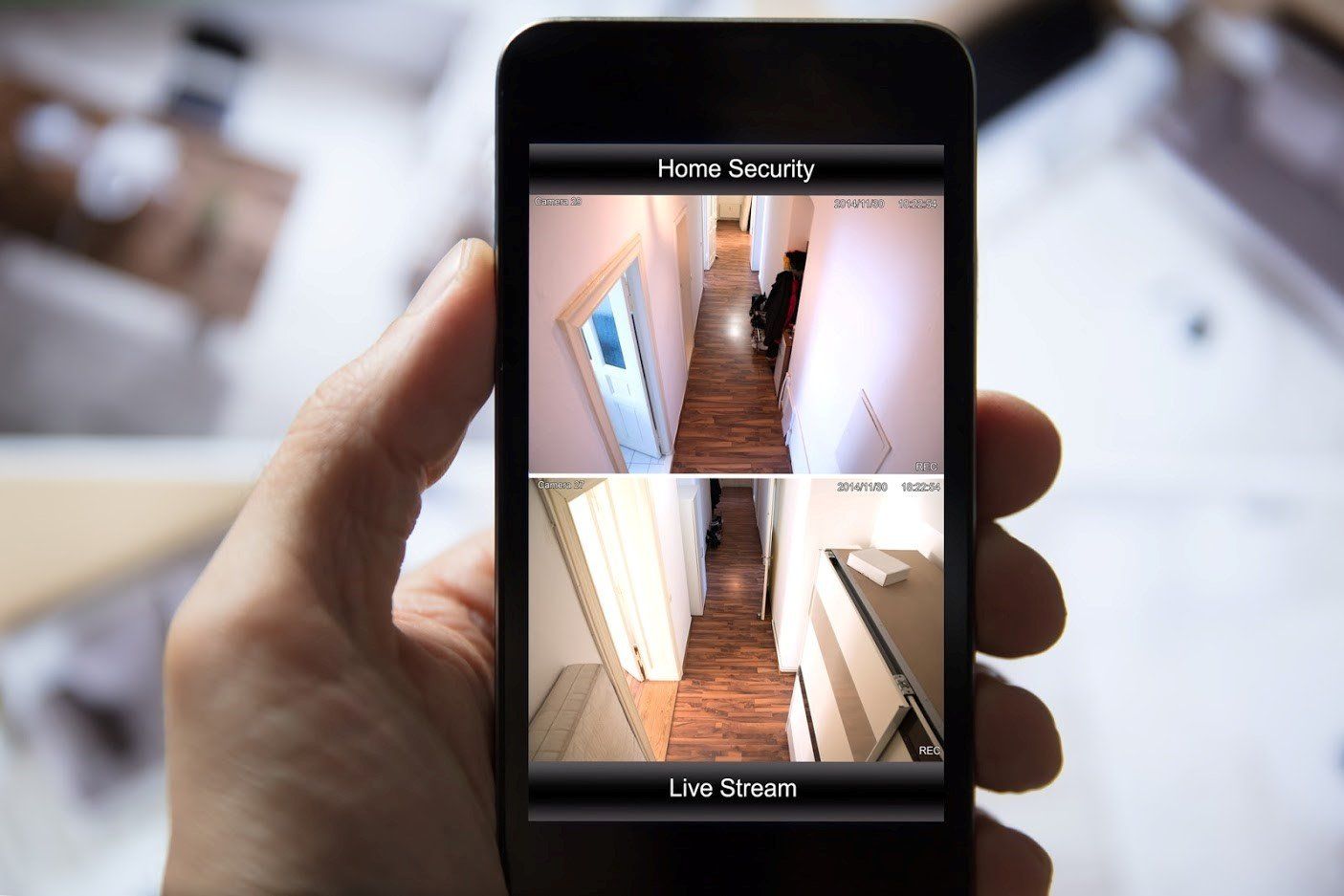 Hand holding a phone displaying a home security app with live camera views of a hallway.