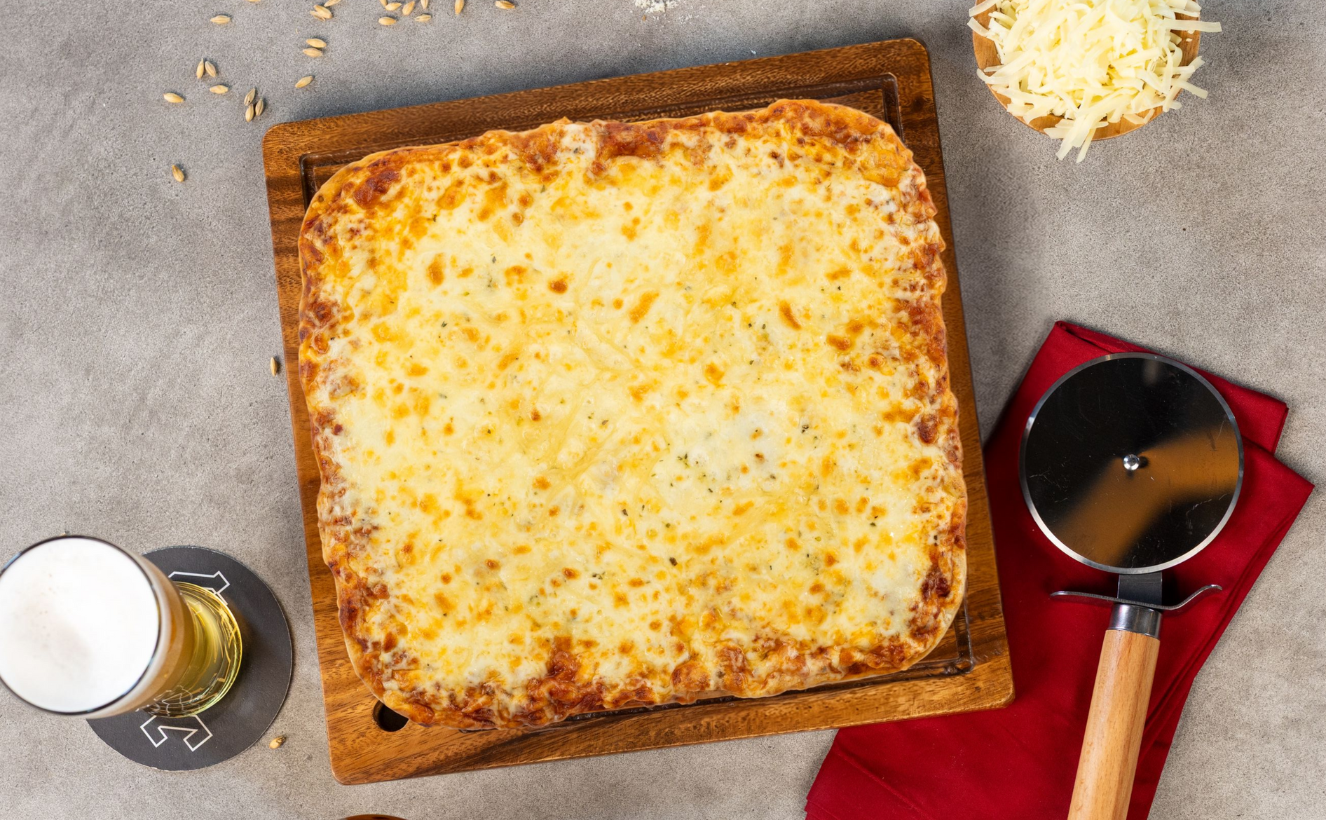 Baked cheesy casserole in a square dish with a spoon, wine glass, and red napkin on a gray table