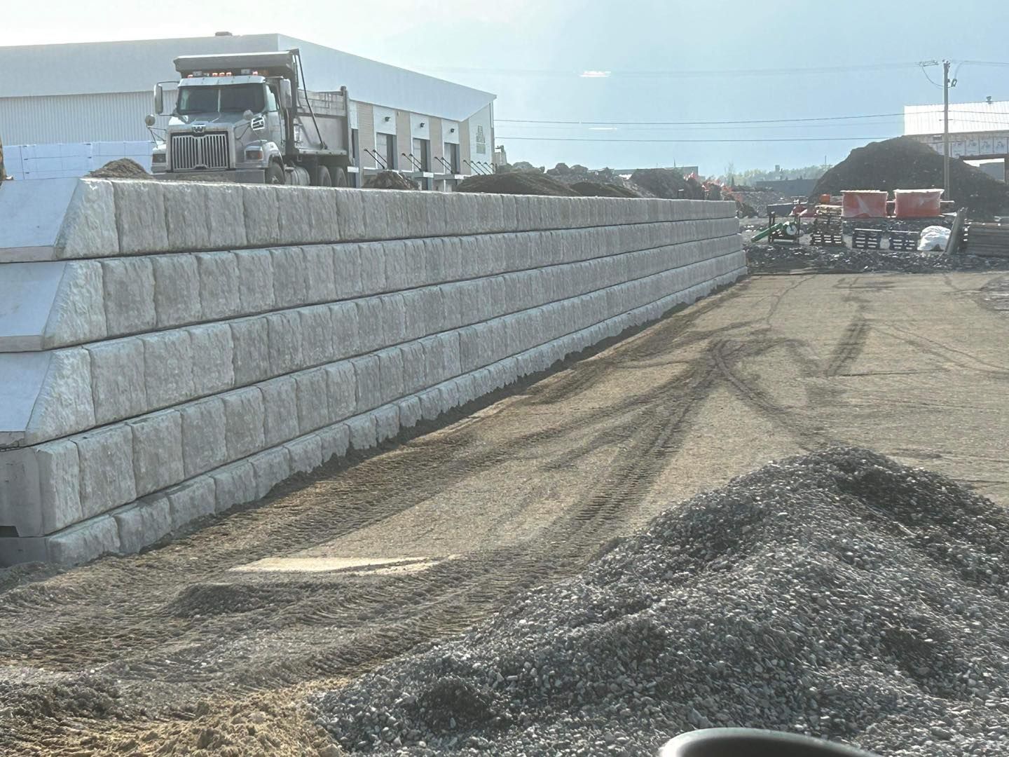 Un grand mur de béton est en cours de construction dans un champ de terre.