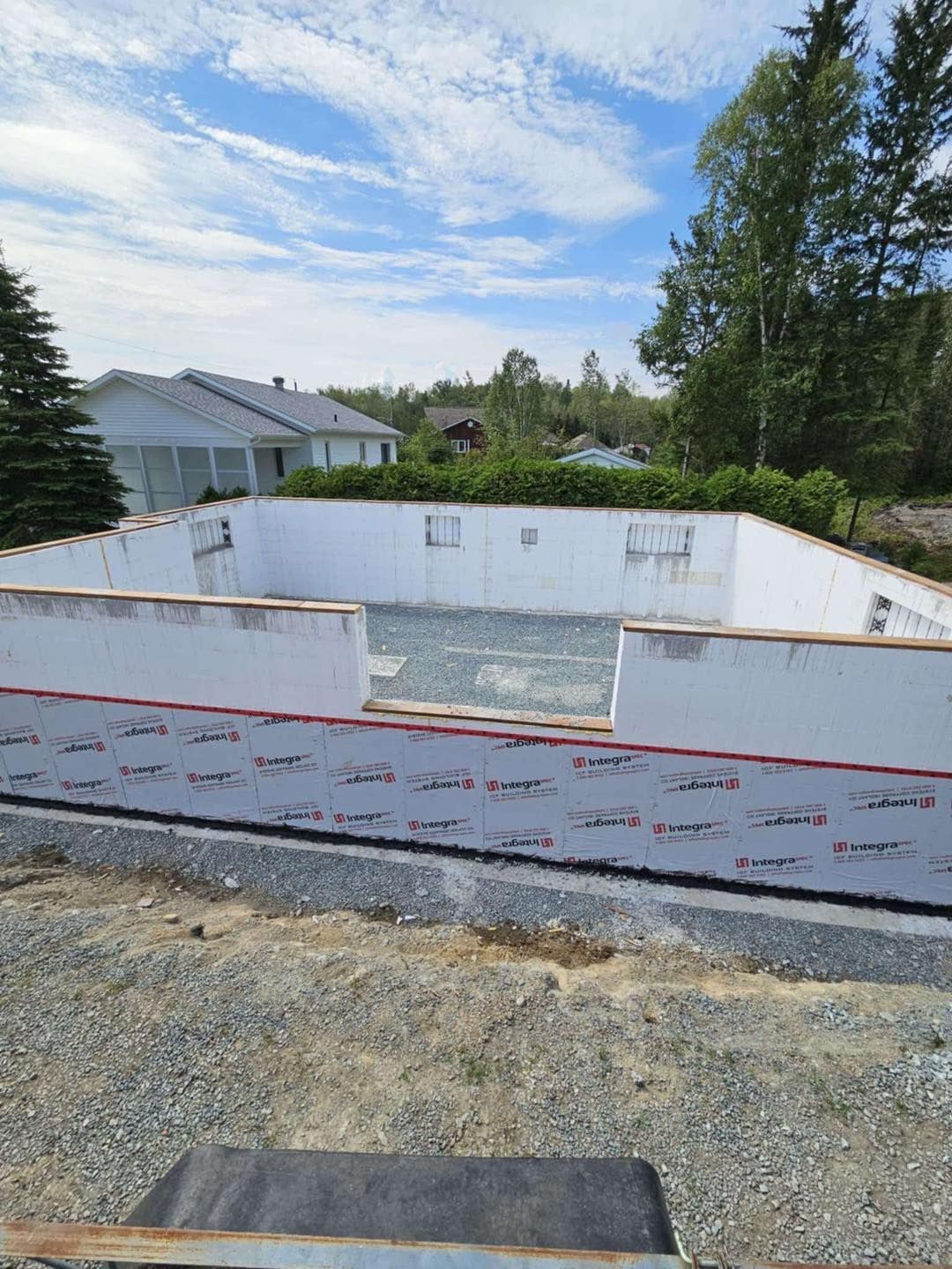 Une grande piscine blanche est en cours de construction au milieu d'un champ de terre.