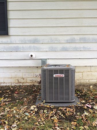 An air conditioner is sitting on the ground in front of a house.