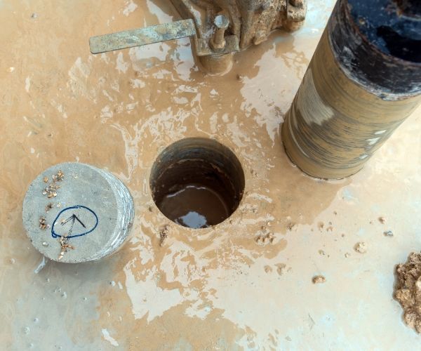 A hole in the ground with a piece of concrete next to it.
