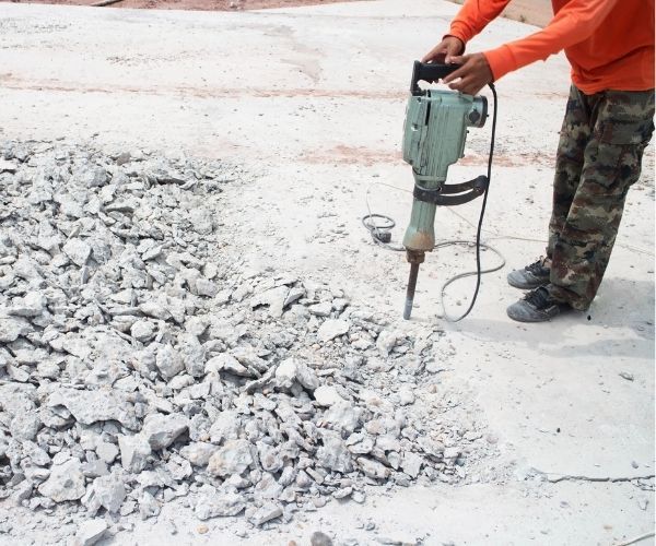 A man is using a hammer on a pile of rocks