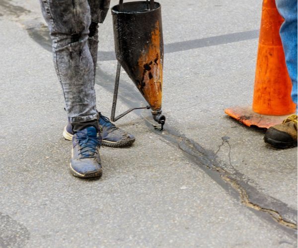 A person is standing next to a cone on the side of the road