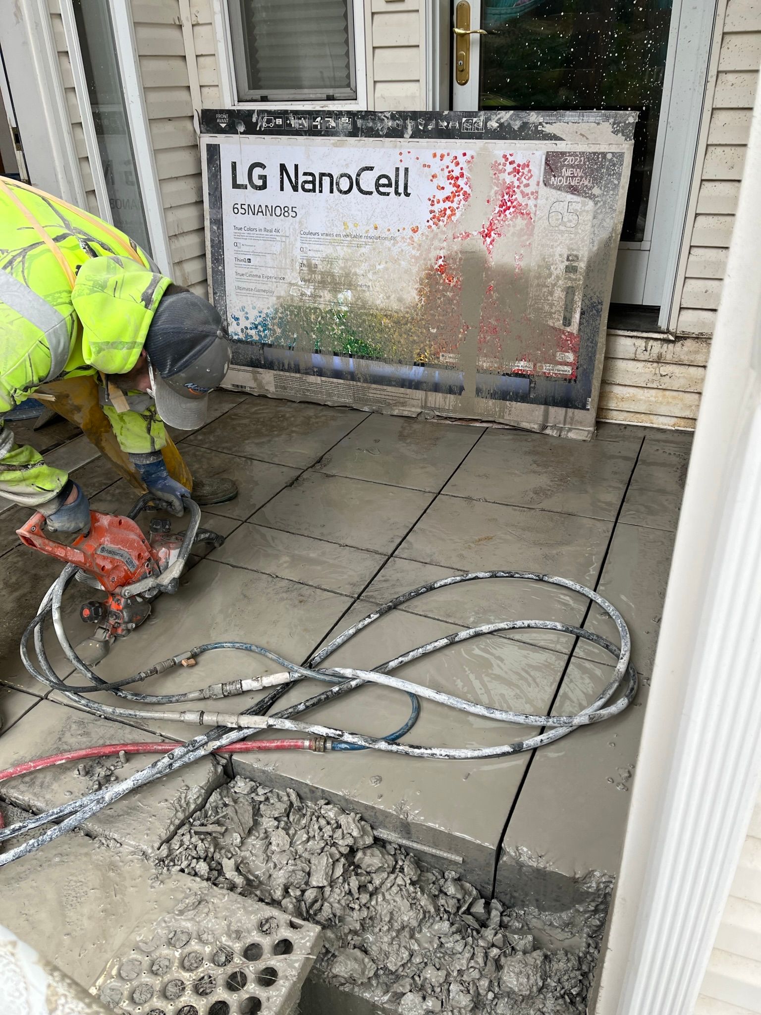 A man is using a concrete saw to cut concrete on a porch.