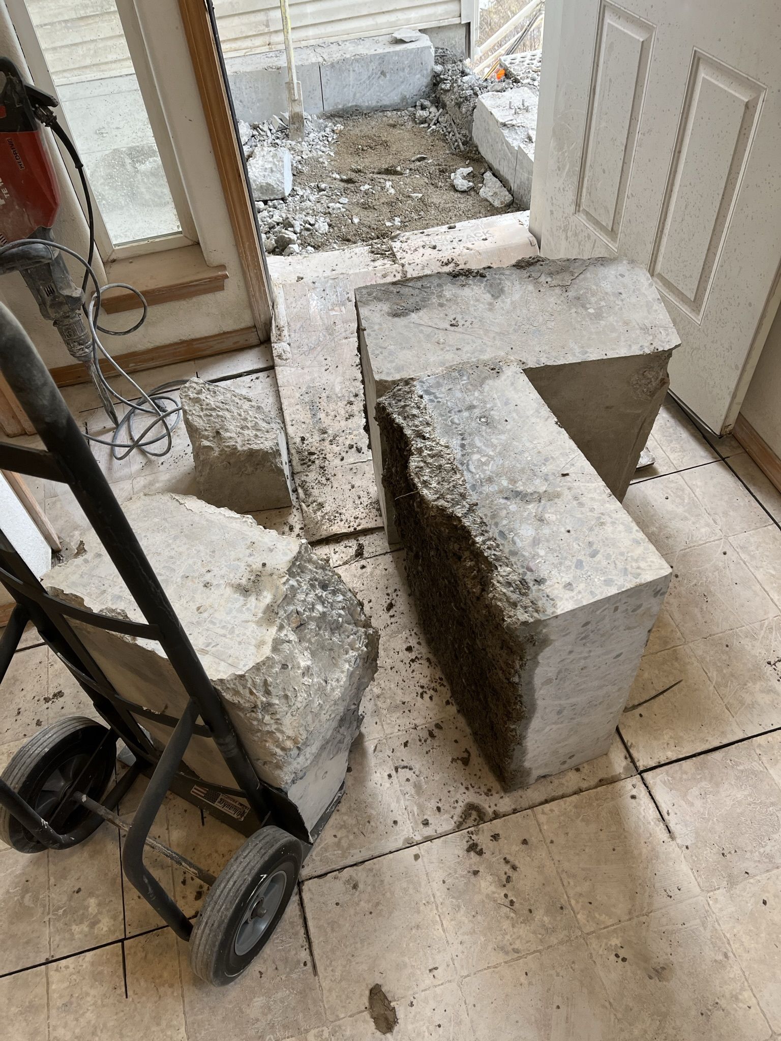 A concrete block is sitting on the floor next to a hand truck.
