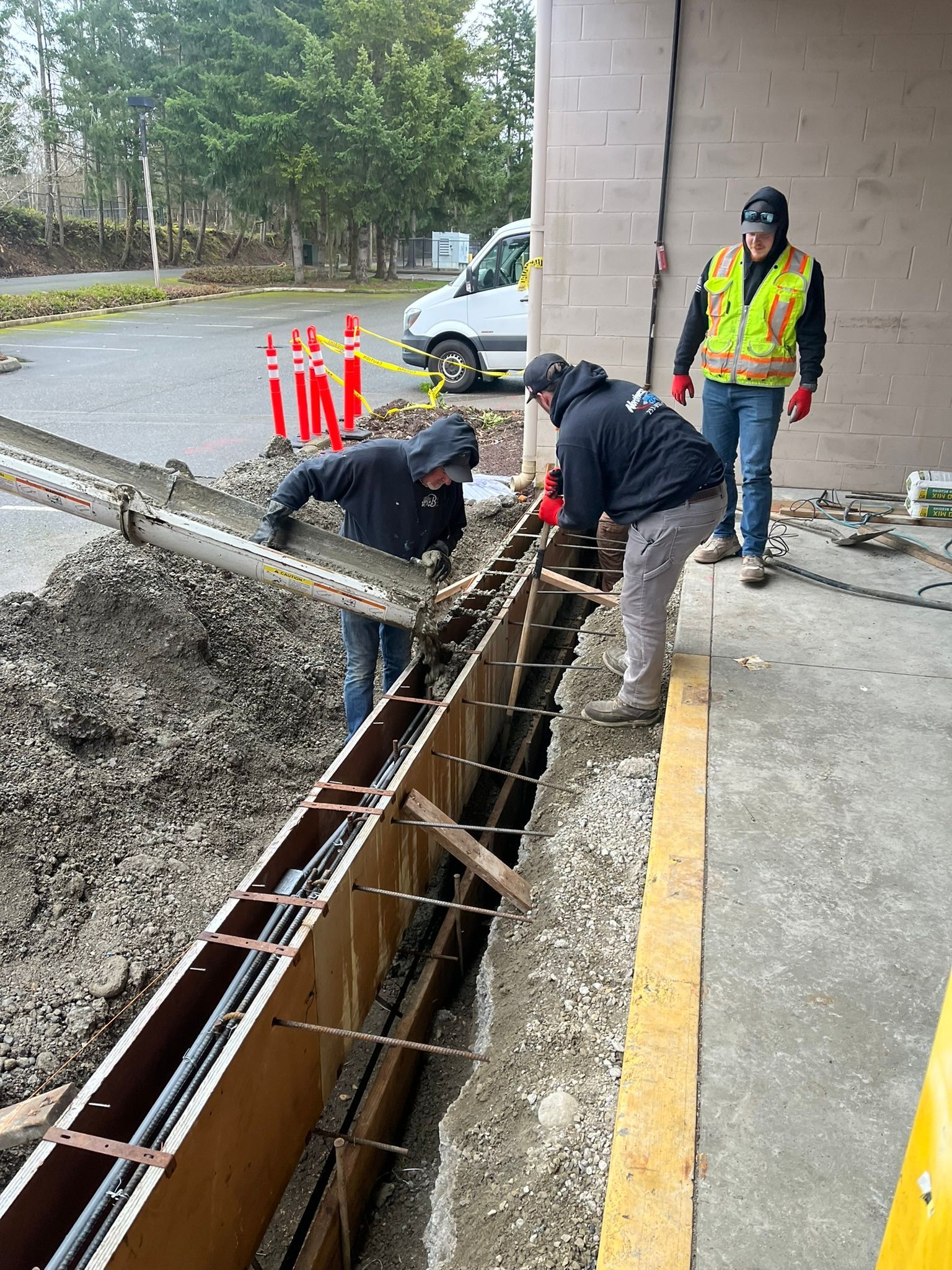 A group of construction workers are working on a concrete wall.