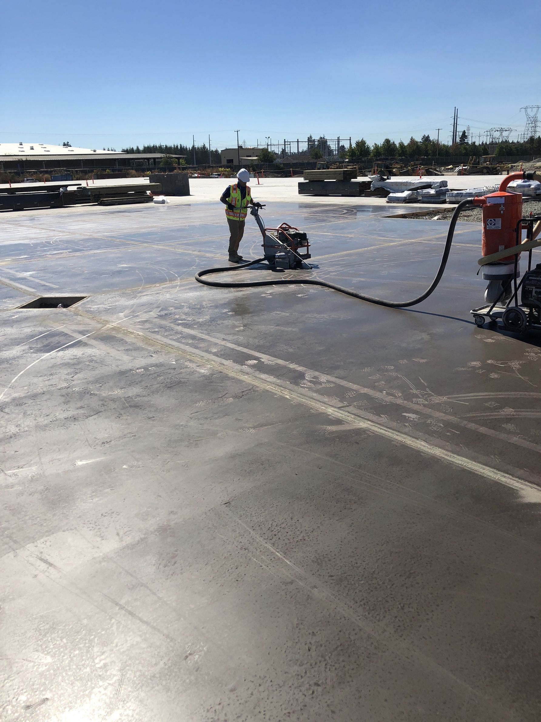 A man is using a machine to cut concrete in a parking lot.