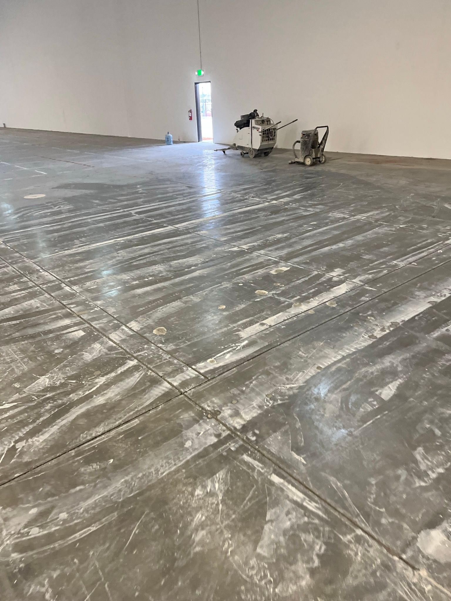 A large empty room with a concrete floor and a machine on it.