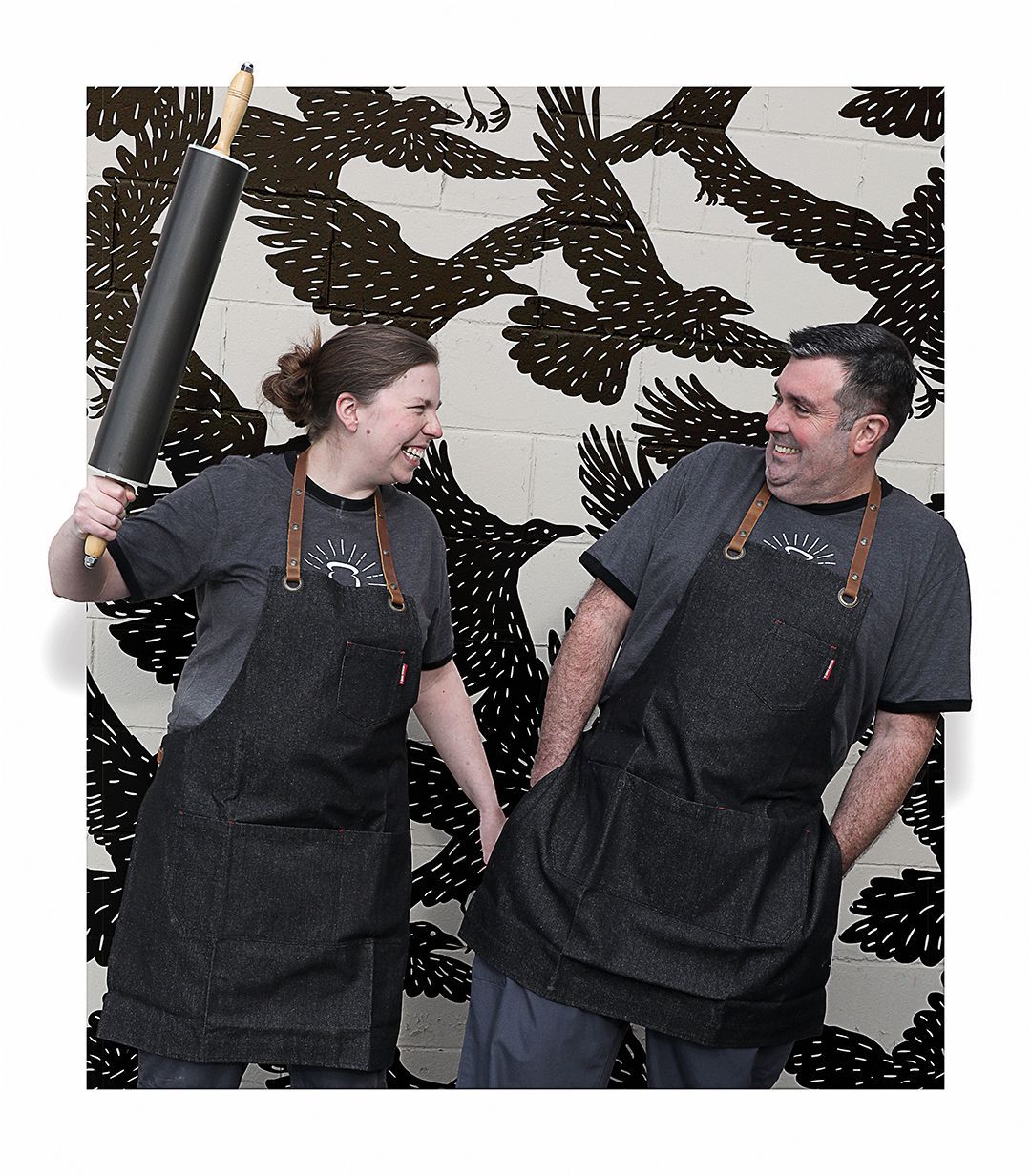 A man and a woman standing next to each other holding rolling pins