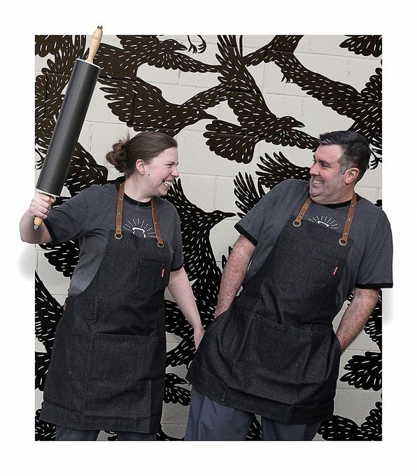 A man and a woman standing next to each other holding rolling pins