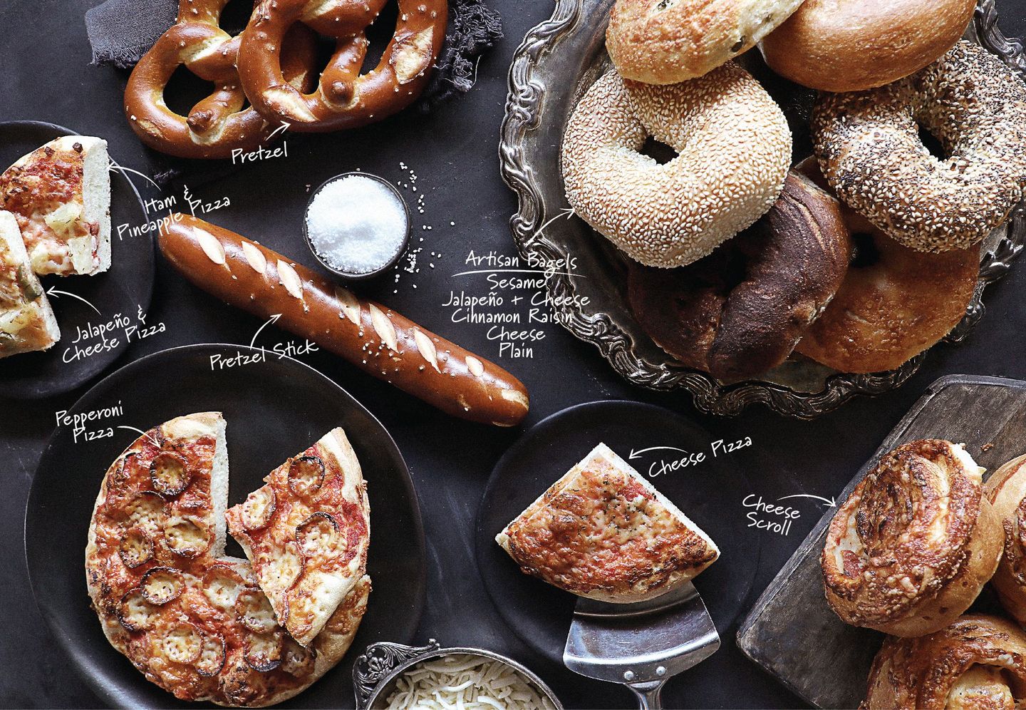 A table topped with a variety of breads and pizzas