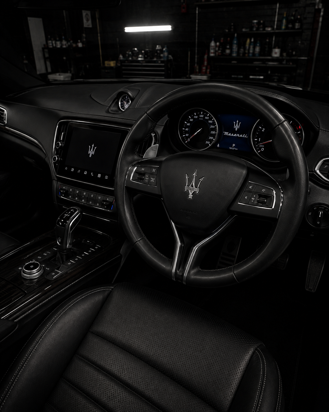 Luxury car interior with black leather seats, steering wheel, and illuminated dashboard at night