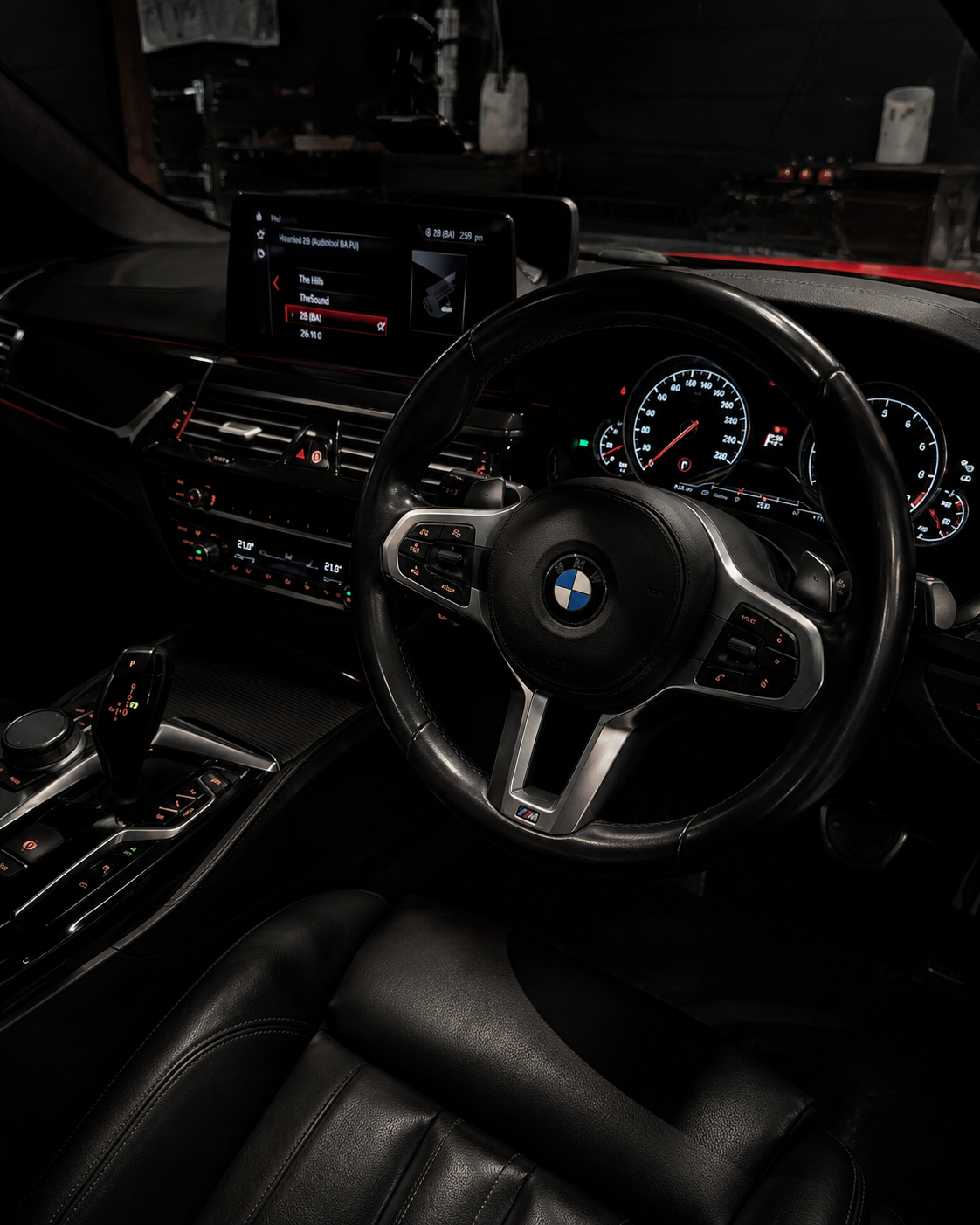 BMW car interior at night, showing the steering wheel, dashboard, and center console.