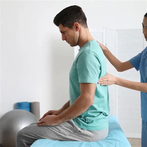Man receiving back examination from a healthcare provider in a clinic setting.