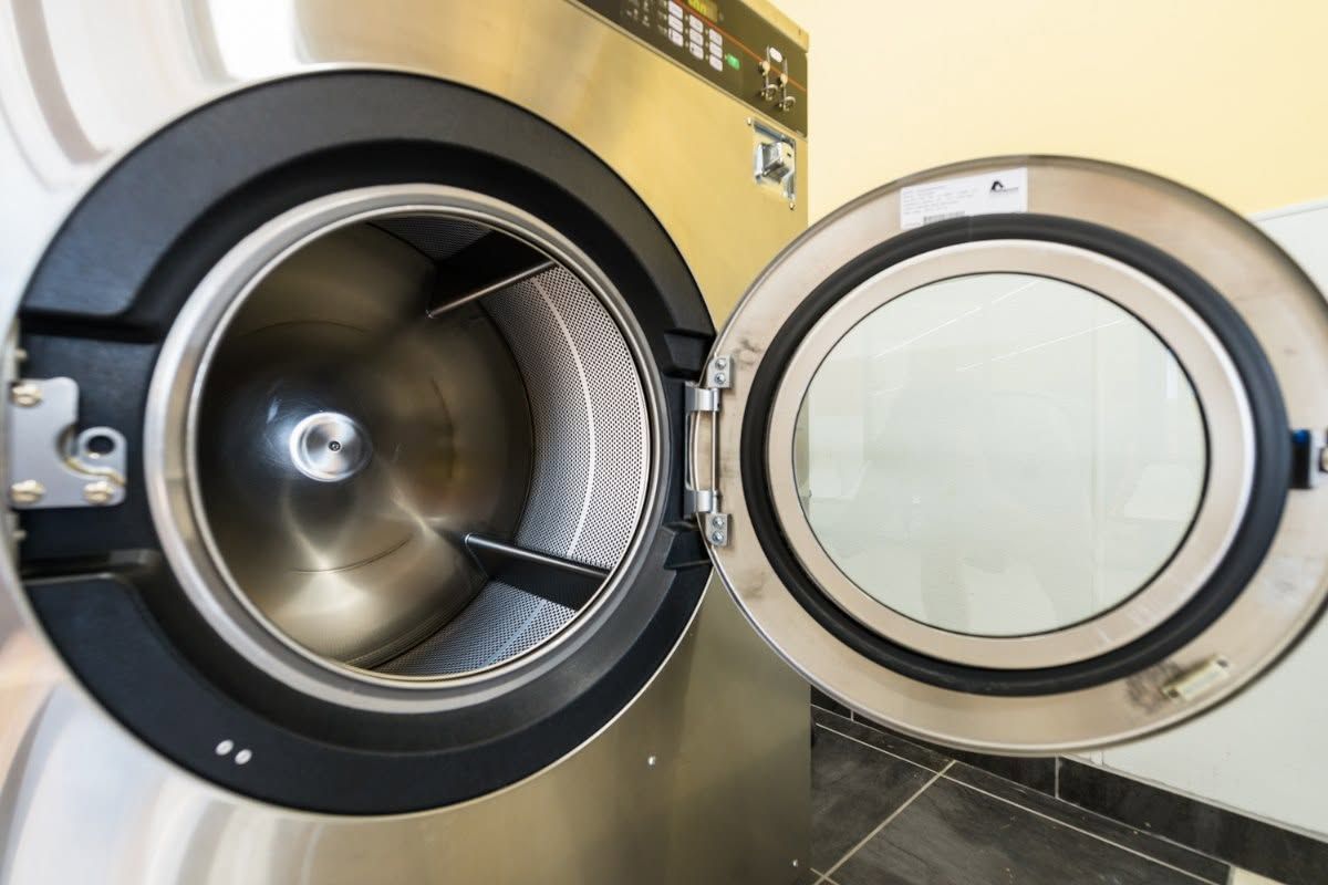 Open front-load washer and dryer drums, one door ajar with lint filter visible.