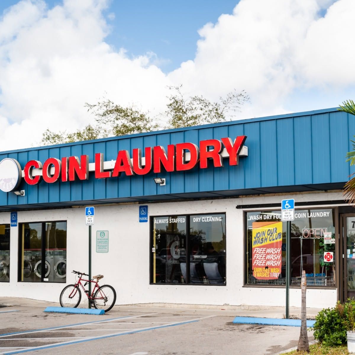 Coin Laundry storefront with red sign, blue facade, and a bicycle parked outside