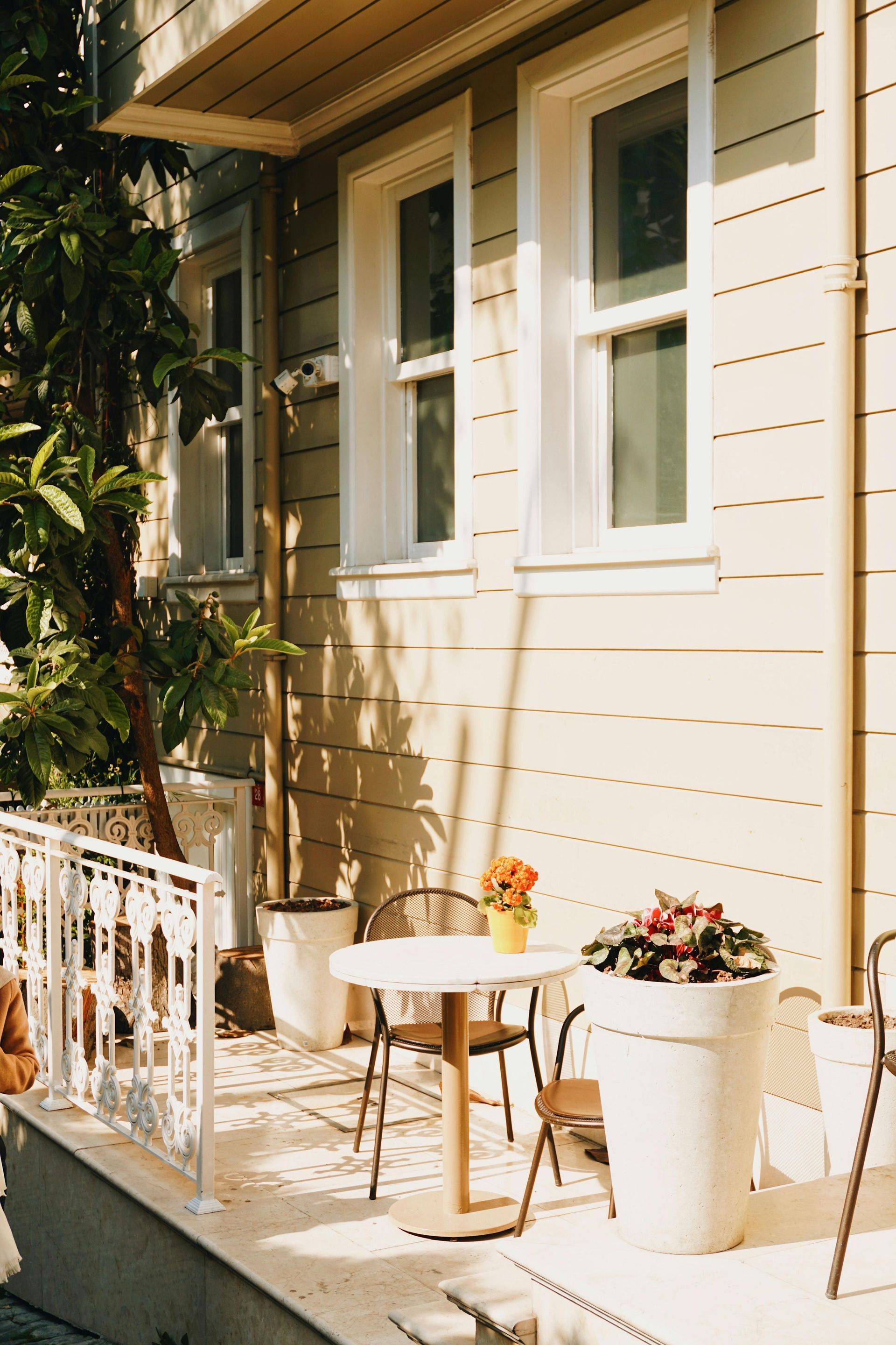 There is a table and chairs on the porch of a house.