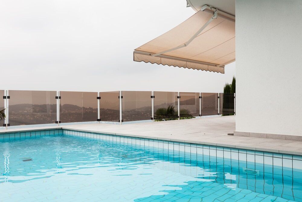 A White Awning is Hanging From the Side of a Building With a Pool — Lismore Curtains & Blinds In Ballina, NSW