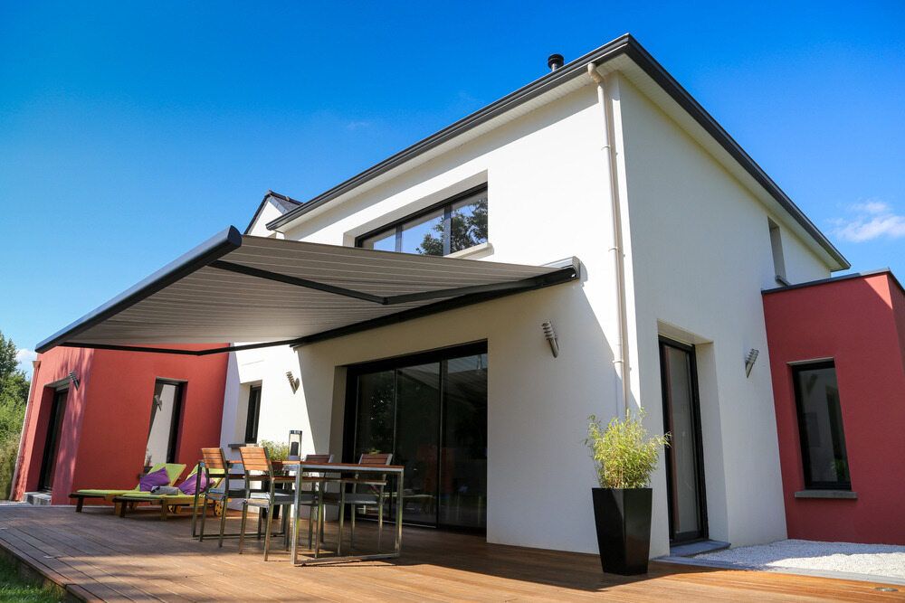 A Patio With a Table and Chairs Next to a White house and an Awning over the Door— Lismore Curtains & Blinds In Lismore, NSW