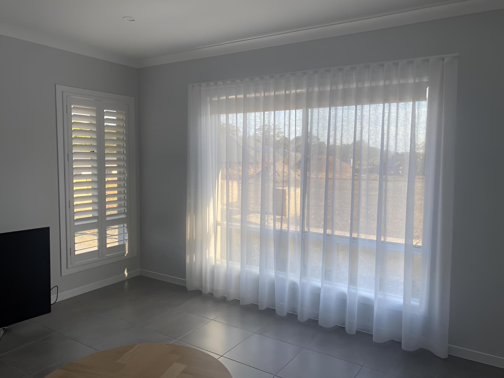A Living Room With White Curtains and Shutters on the Windows — Lismore Curtains & Blinds In Ballina, NSW