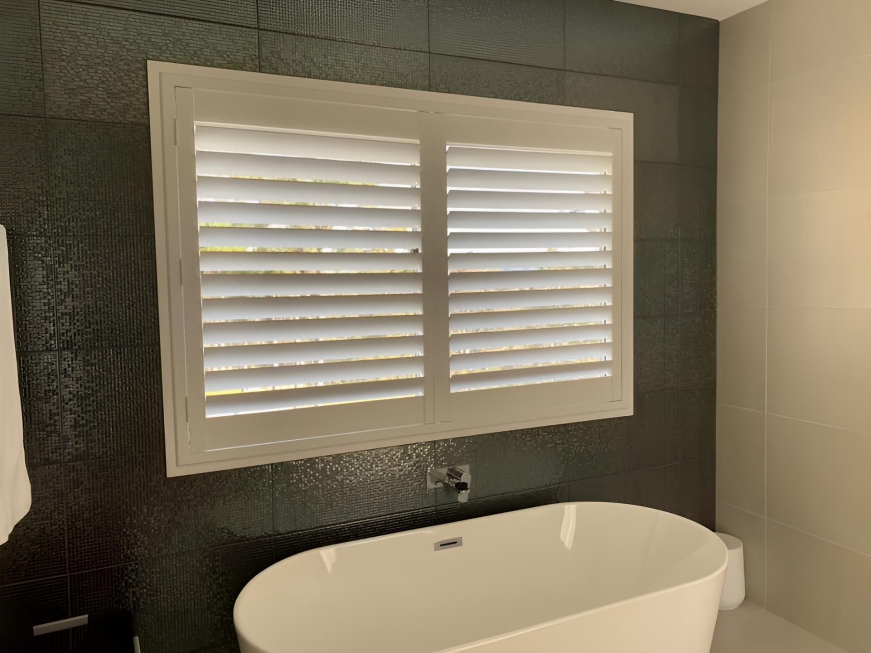 A Bathroom With a Bathtub and a Window With Shutters — Lismore Curtains & Blinds In Ballina, NSW