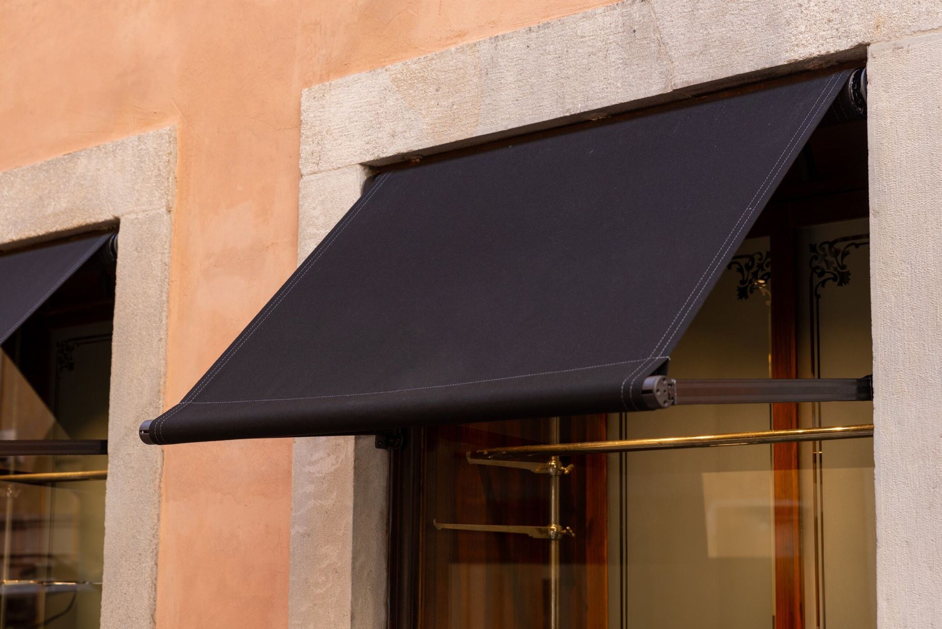 A Black Awning on the Windows of a Orange Building — Lismore Curtains & Blinds In Lismore, NSW